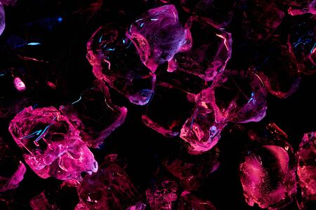 top view of transparent ice cubes with purple lighting isolated on blackの写真素材