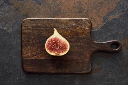 top view of ripe cut delicious fig on wooden cutting board on stone backgroundの写真素材
