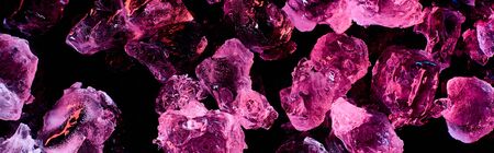 panoramic shot of transparent ice cubes with purple illumination isolated on black