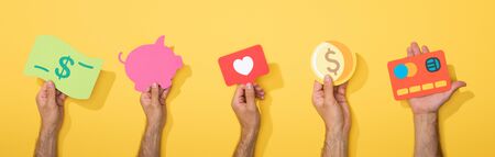 panoramic shot of men holding colorful paper icons on yellowの写真素材