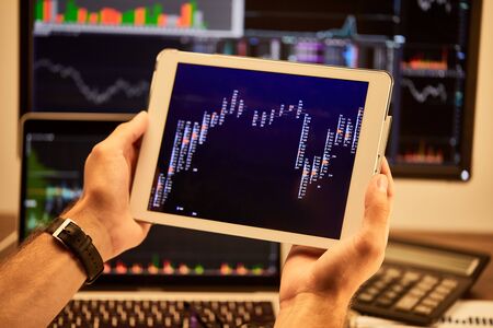 cropped view of man holding digital tablet with graphs and chartsの写真素材