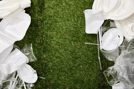 top view of crumpled plastic cups and plates on grass with copy spaceの写真素材