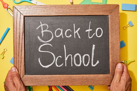 cropped view of man holding chalkboard with back to school lettering