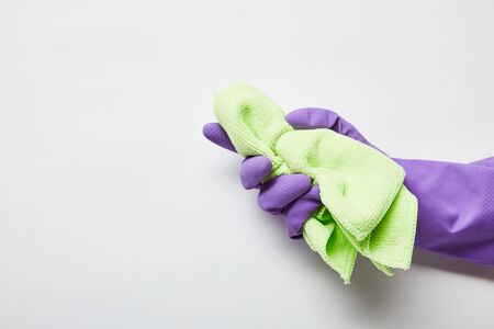 cropped view of man in purple rubber glove holding green rag