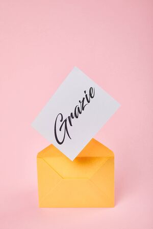 yellow envelope with grazie word on white card on pink backgroundの写真素材