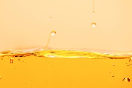 yellow bright liquid with drops and bubbles isolated on yellowの写真素材