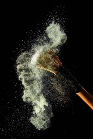 cosmetic brush with colorful powder explosion on black backgroundの写真素材