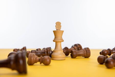 chess king near other figures on yellow surface isolated on whiteの写真素材