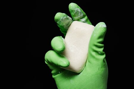 cropped view of man in green rubber glove holding soap isolated on blackの写真素材