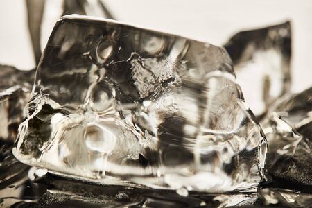 close up view of transparent melting ice cubes with drops