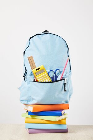 blue backpack with supplies in pocket on books isolated on whiteの写真素材