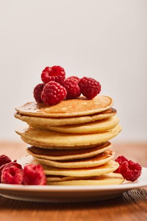 selective focus of tasty pancakes with raspberries on plate isolated on greyの写真素材