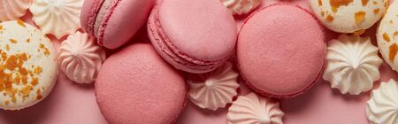 Delicious assorted macaroons with small pink and white meringues on pink background