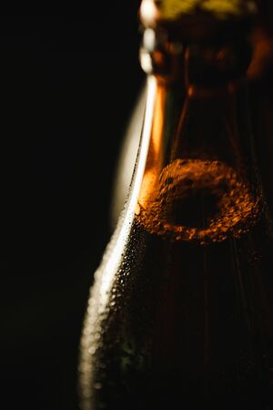 close up view of wet bottle of beer with bubbles isolated on blackの写真素材