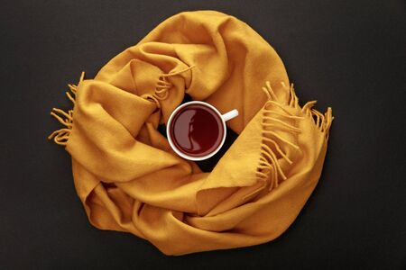 top view of tea in mug in cozy scarf on black backgroundの写真素材