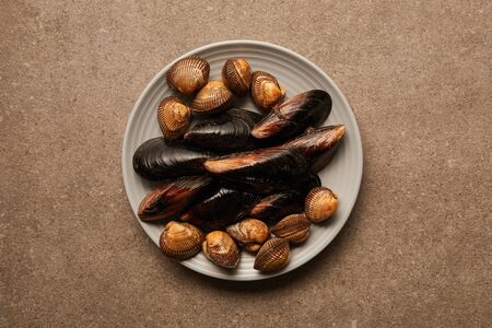 top view of plate with uncooked cockles and mussels on surfaceの写真素材