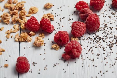 scattered raspberries, chia seeds and oat flakes on white wooden tableの写真素材