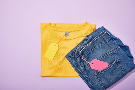 top view of colorful sale tags on t-shirt and jeans on violetの写真素材