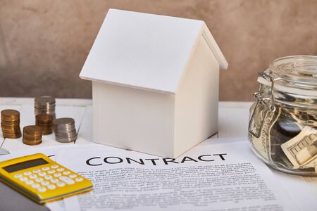 house model, coins, yellow calculator near contract and moneybox, real estate conceptの写真素材