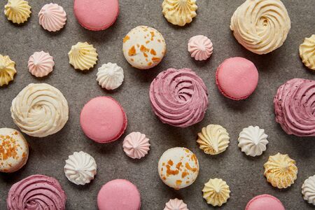 Top view of assorted pink white and yellow macaroons with meringues on gray backgroundの写真素材