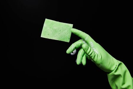 cropped view of man in green rubber glove with sponge on black backgroundの写真素材