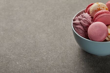 Delicious pink and white macaroons with zephyr in blue bowl on gray backgroundの写真素材