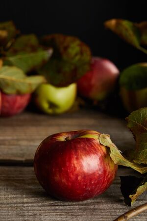 red ripe apples with leaves on wooden surface isolated on blackの写真素材