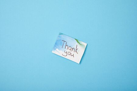 greeting card with thank you lettering on blue background with copy spaceの写真素材
