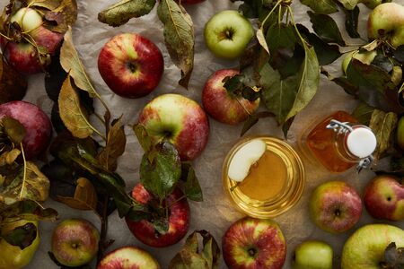 top view of ripe apples with leaves near glass and bottle of cider