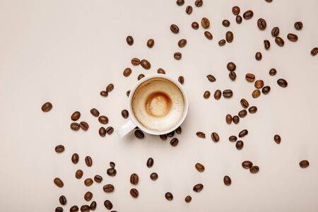 top view of coffee cup with foam on beige background with coffee grainsの写真素材
