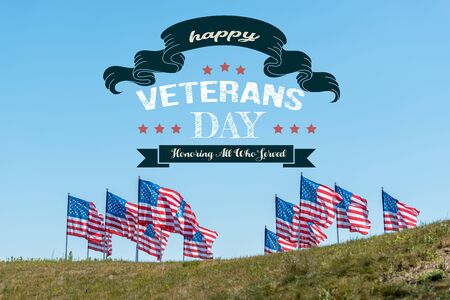 national american flags on green grass against blue sky with happy veterans day, honoring all who served illustrationの写真素材
