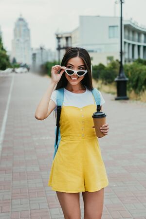 asian woman holding paper cup with coffee and looking awayの写真素材