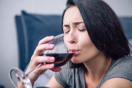 selective focus of lonely depressed woman drinking wine at homeの写真素材