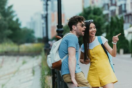 handsome man looking away and asian woman pointing with fingerの写真素材
