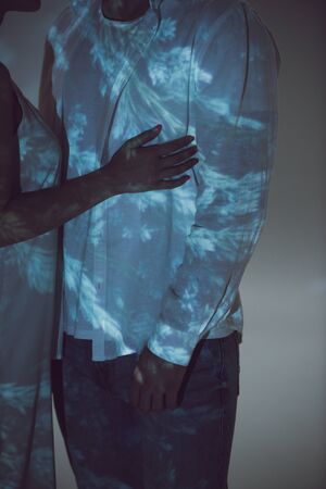 cropped view of two people standing in darkness and hugging each other