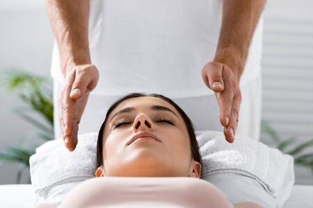 cropped view of healer standing near patient on massage table and cleaning auraの写真素材