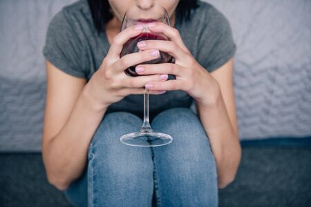 cropped view of depressed woman drinking wine at homeの写真素材