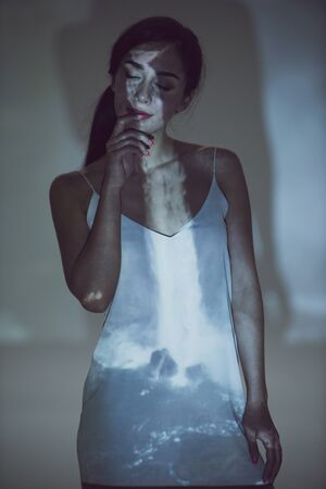 beautiful woman standing in darkness with closed eyes in pose