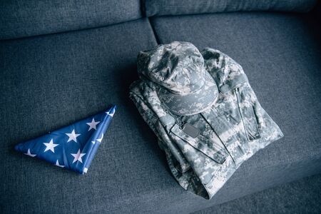 military clothing and folded american flag on couch at homeの写真素材