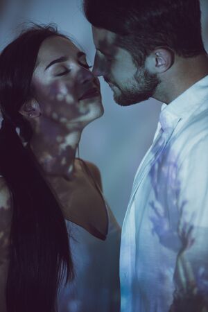cute couple standing in darkness close to each other