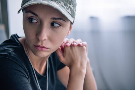 depressed woman in military uniform and cap at home with copy spaceの写真素材