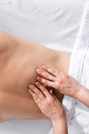 cropped view of masseur and shirtless man lying on massage table