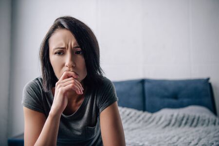 beautiful depressed woman touching chin at home with copy spaceの写真素材