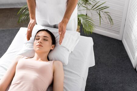 cropped view of healer standing near patient on massage table and cleaning auraの写真素材