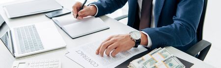 top view of businessman holding pen near contract and money in office