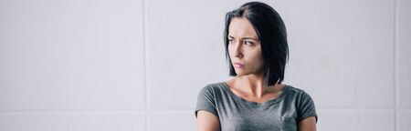 panoramic shot of depressed brunette woman looking away at home