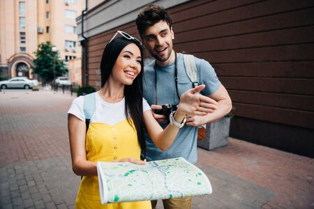 handsome man looking away and asian woman holding map