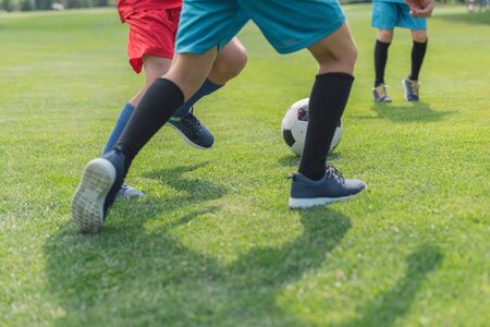 cropped view of boys playing football on grassの写真素材