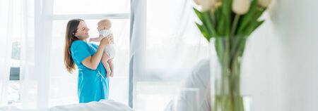 panoramic shot of attractive and young mother holding her child in hospitalの写真素材
