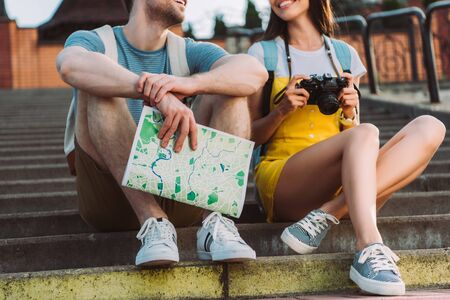 cropped view of woman holding digital camera and handsome man holding mapの写真素材
